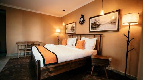 a bedroom with a large bed with white sheets and orange pillows at Skojet Boutique Hotel in Ruhengeri