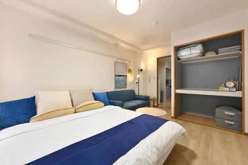a bedroom with a large bed and a blue couch at Haniwa Stay Josai in Nagoya