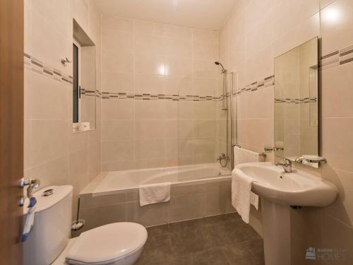 a bathroom with a toilet and a tub and a sink at Hillock Residence Apartments in Marsalforn
