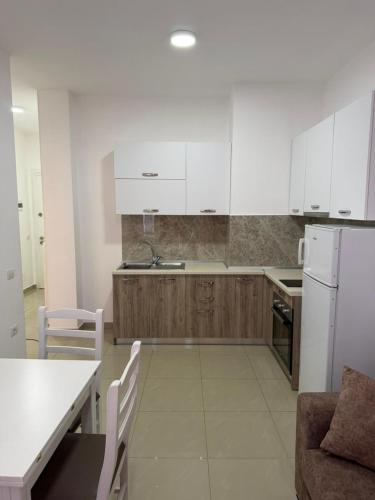 a kitchen with white cabinets and a table and chairs at Elois Apartments in Shëngjin