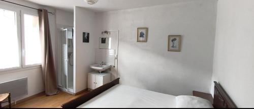 a white bathroom with a sink and a bed at la tute de l'ours in Roquefeuil