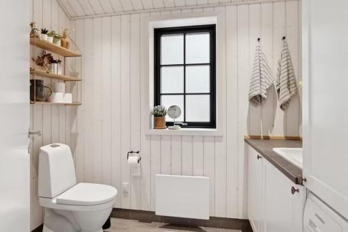 a white bathroom with a toilet and a window at Nordic Nature Hideaway in Yderby