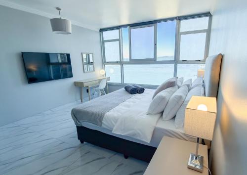 a bedroom with a large bed with a large window at Sea Esta On Beach in Strand