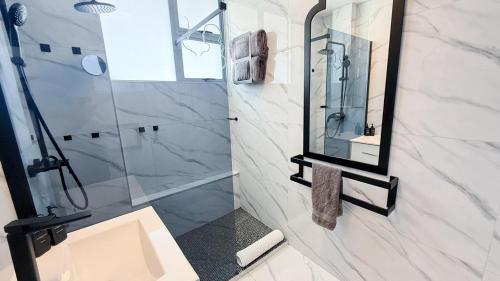 a bathroom with a shower and a sink and a mirror at Sea Esta On Beach in Strand