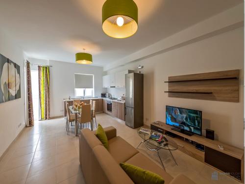 a living room with a couch and a tv and a kitchen at Hillock Residence Apartments in Marsalforn