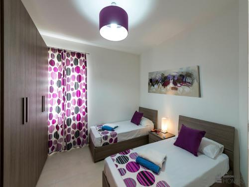 a bedroom with two beds with purple pillows at Hillock Residence Apartments in Marsalforn