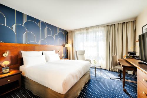 a hotel room with a bed and a desk at Welcome Parkhotel Bochum in Bochum