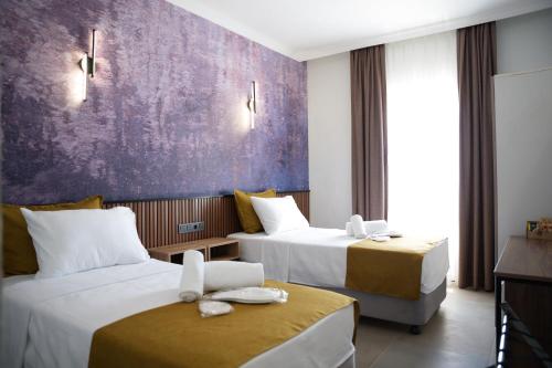 a hotel room with two beds and a purple wall at Quatro Life Hotel in Bodrum City