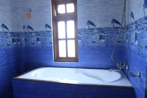 a blue bathroom with a bath tub with a window at Greenery View Point Resort in Kathmandu