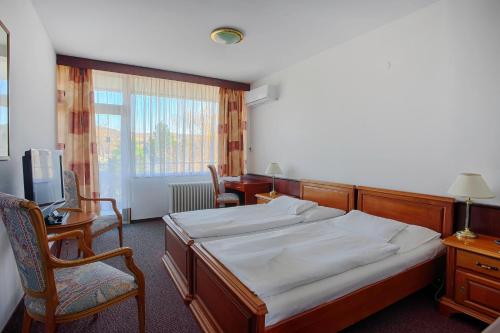 a bedroom with a bed and chairs and a window at Ensana Splendid in Piešťany