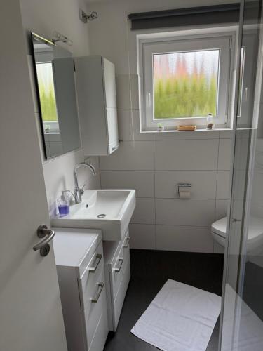 a white bathroom with a sink and a window at Ferienhaus SPO 54 grad in Böhl