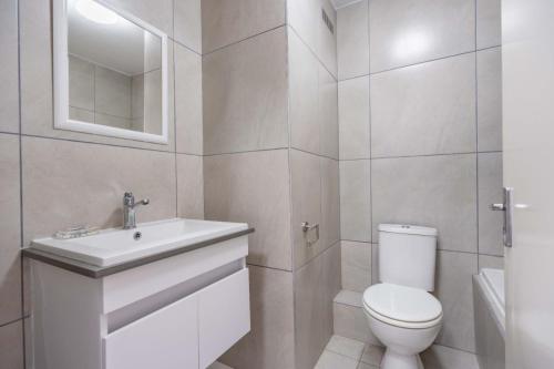 a white bathroom with a toilet and a sink at Cozumel 216 in Umdloti
