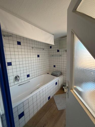 a bath tub in a bathroom with white tiles at Über der Brücke in Melsungen