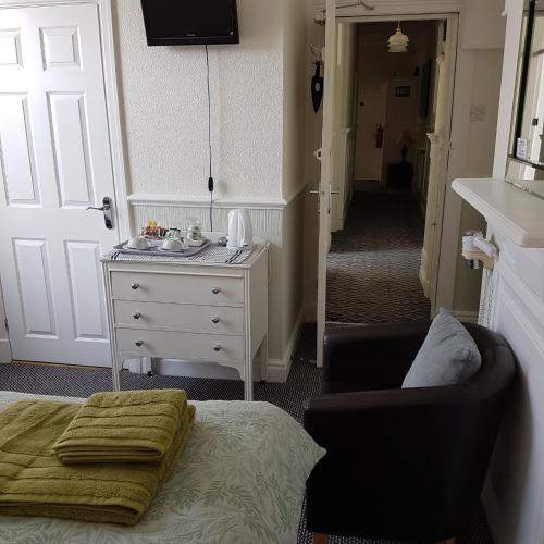a bedroom with a bed and a chair and a dresser at Binton Guest House in Filey