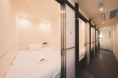 a small room with a bed and a walk in closet at Takt Jongno Female Only Capsule Hotel in Seoul