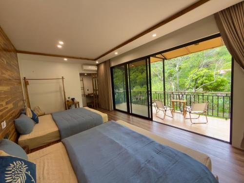 a bedroom with two beds and a balcony at Suối Mộc Ecostay - Mộc Châu in Mộc Châu