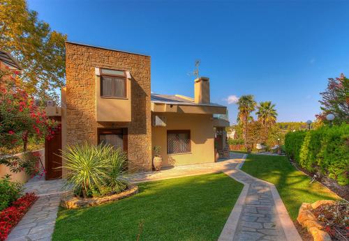 a house with a green lawn in front of it at Artemisia Villa, Anthology Villas in Sani, ex Sani Luxury Villas Collection in Sani Beach