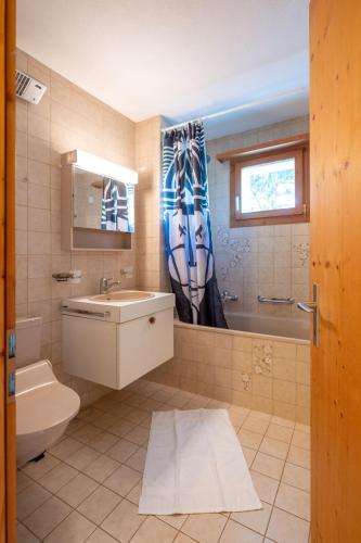 a bathroom with a sink and a toilet and a window at Garden apartment with mountain views & barbecue in Lenz