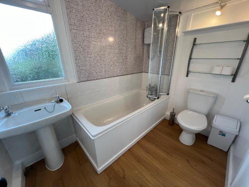 a bathroom with a tub and a toilet and a sink at The Lodge Ellary in Lochgilphead