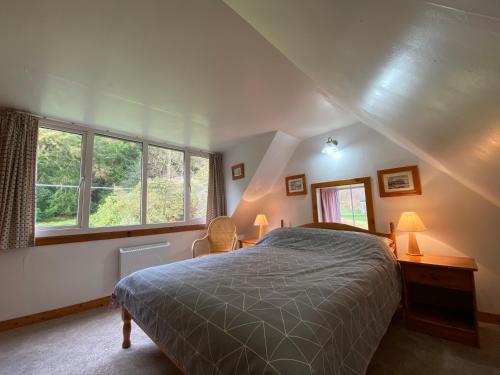a bedroom with a large bed and two windows at The Lodge Ellary in Lochgilphead