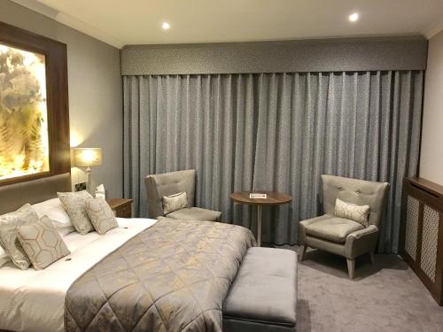 a hotel room with a bed and two chairs at The Lodge Hotel in Coleraine