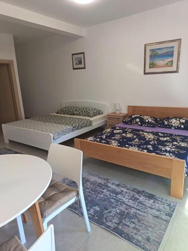 a bedroom with two beds and a table and a table and chairs at Apartmani Miletić in Jelsa