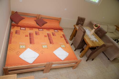 a bedroom with a bed with an orange bedspread and a table at Aurum Etno & Spa in Smederevo