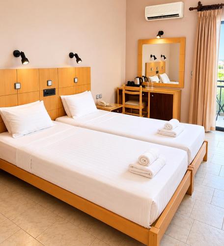 two beds in a room with two towels on them at Ermioni Hotel in Georgioupolis