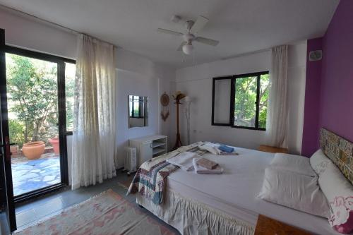 a bedroom with a bed and a large window at Mimas Garden Apartments in Karaburun