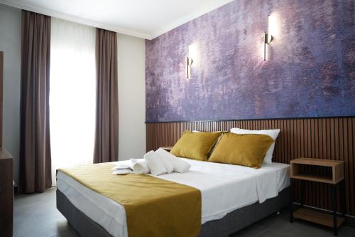 a bedroom with a large bed with a purple wall at Quatro Life Hotel in Bodrum City