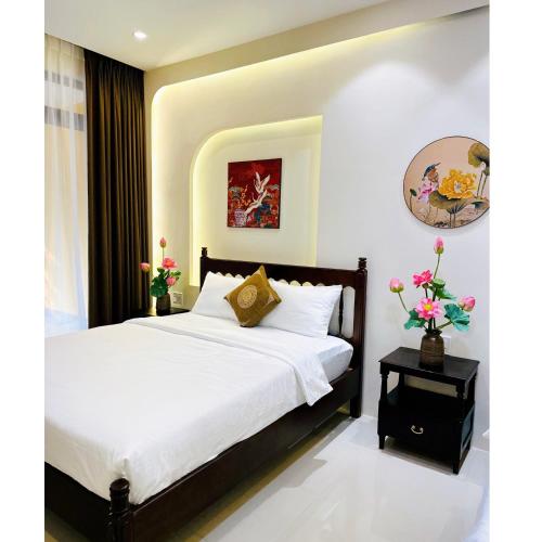a bedroom with a bed with white sheets and flowers at HueS Home in Hue