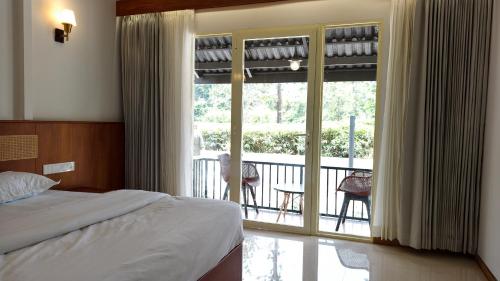 a bedroom with a bed and a view of a balcony at Estate IV - Saffron Suite - Tea Estate Stay in Vythiri