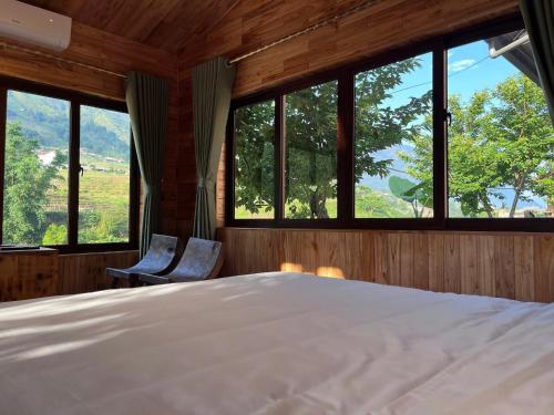 a bedroom with a large bed and windows at Zay Riverside House in Tả Van