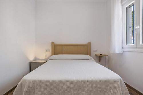 a white bed in a white bedroom with a window at Casa de 10 - 2a in Vejer de la Frontera