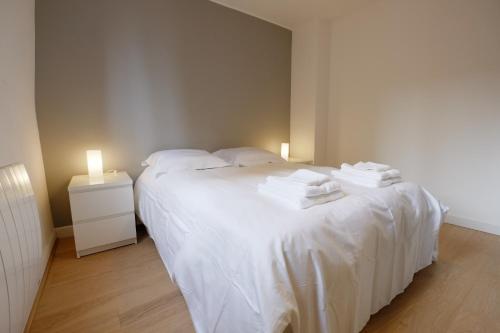 a bedroom with two beds with white sheets and two lights at Appartement Plaisance in Lille