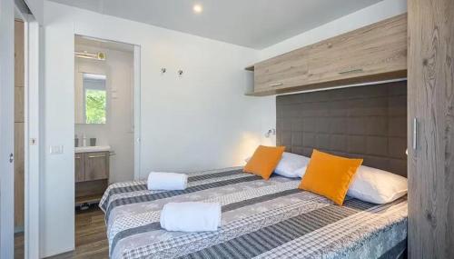 a bedroom with two beds with orange and white pillows at Camping Bijela Uvala - Roan in Poreč