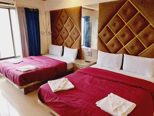 two beds in a hotel room with red sheets at Roshan Residency in Matheran