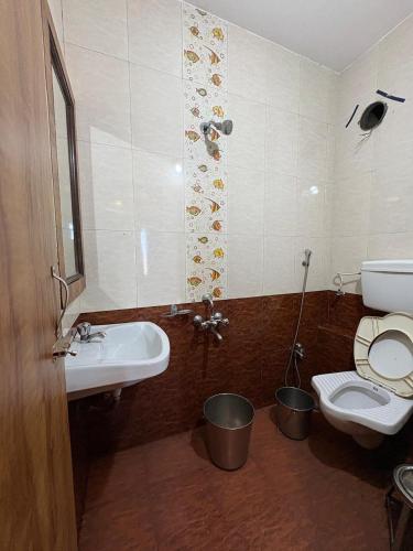 a bathroom with a sink and a toilet with buckets at Roshan Residency in Matheran