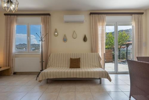 a living room with a couch and two windows at Villa Melenia 1 in Agia Pelagia
