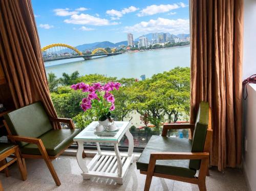 a room with a table and chairs and a view of a river at Hồng Phúc 7 Hotel in Danang