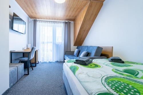 a hotel room with a bed and a desk and a table at Pensjonat Perła in Grzybowo