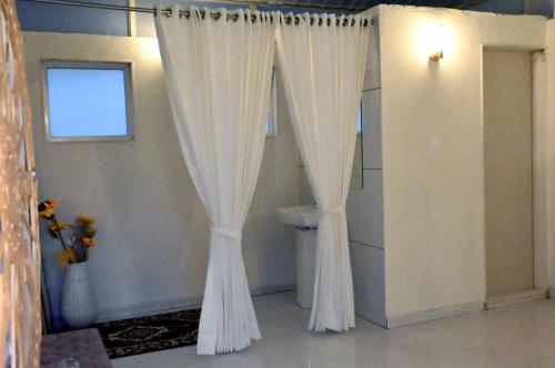 a white shower curtain in a room with a toilet at WayFare Stud Farm & Resort in Nashik