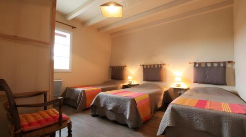 a room with three beds and a chair and a window at Gite Karrikartea in Saint-Pée-sur-Nivelle