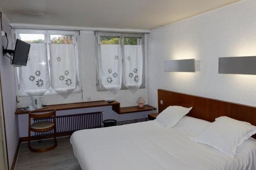 a bedroom with a white bed and two windows at Hôtel le Relais in Eu