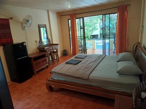 a bedroom with a bed and a desk and a window at Buffalo Bay Vacation Club in Ko Phayam