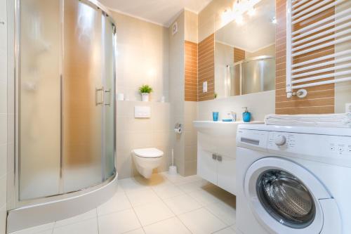 a bathroom with a washing machine and a toilet at Apartament Darłówko in Darlowko