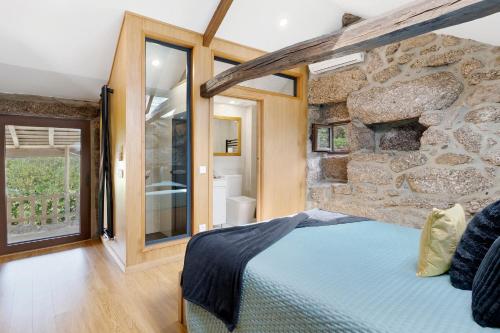 a stone walled bedroom with a bed and a bathroom at Casa do Moinho in Aboim