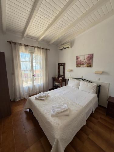 a bedroom with a white bed with two towels on it at Eleni's Apartments in Barbati