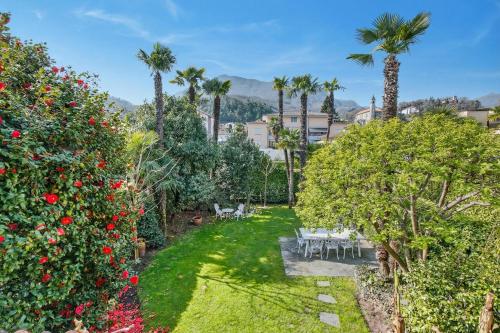 a garden with palm trees and chairs and flowers at Casa Viola Losone for 8 - Happy Rentals in Losone