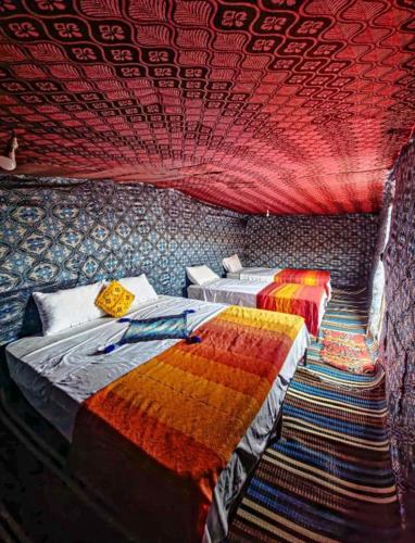 two beds in a room with a red ceiling at Moon Dunes camp in Adrouine